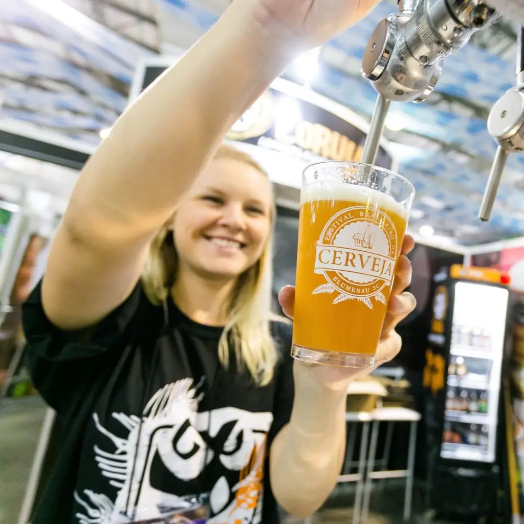 Mulher servindo uma cerveja em um copo com a logo do festival brasileiro da cerveja